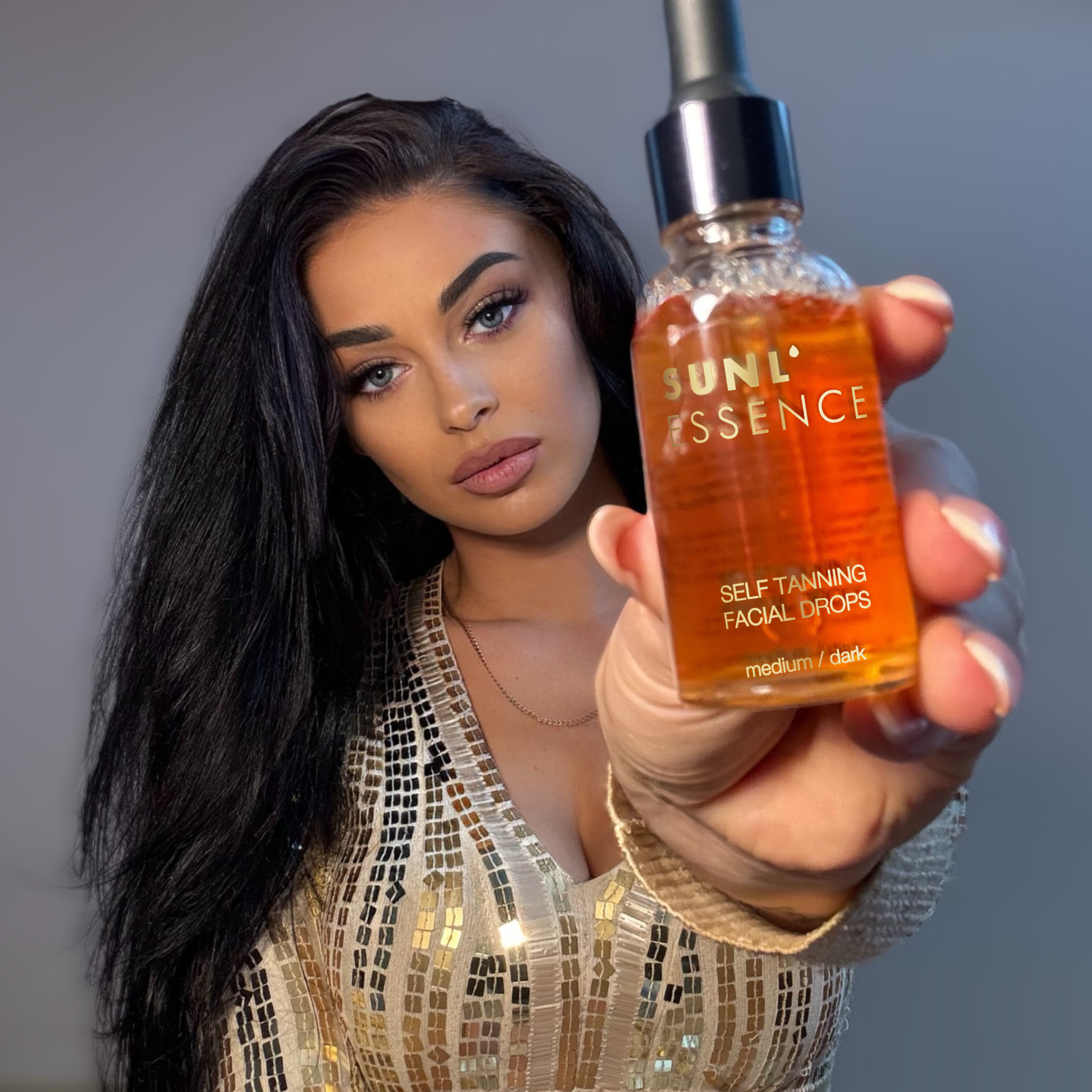 Modelka prezentuje z bliska kropelki samoopalające Onyx Sunl’essence. Serum do twarzy tworzy zdrowy, równy odcień skóry bez smug.
