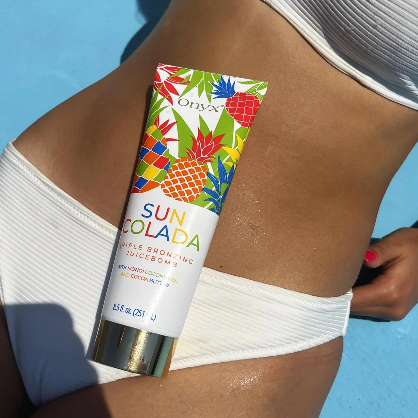 Balsam Onyx Suncolada leży na brzuchu kobiety w białym bikini, widoczna równomierna, złocista opalenizna i gładka skóra