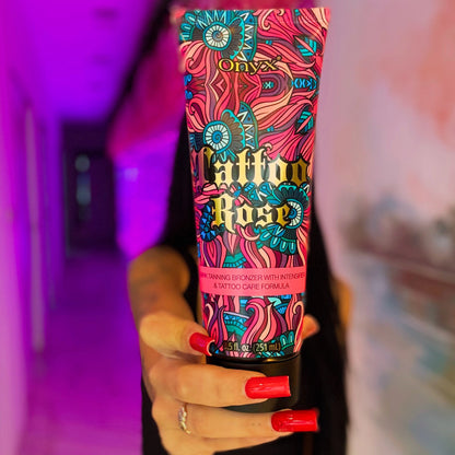 Zbliżenie na balsam do opalania Onyx Tattoo Rose trzymany przez kobietę z czerwonymi paznokciami, kolorowe oświetlenie tła w odcieniach fioletu i różu